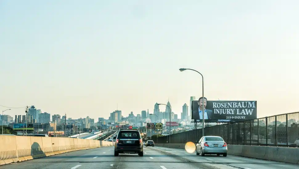 Cars on the highway with "Rosenbaum Injury Law" billboard in the far right.