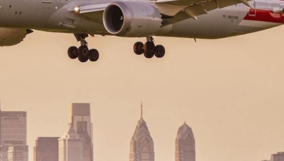 An American Airlines jet approaches landing with the skyline of Philadelphia in the background.