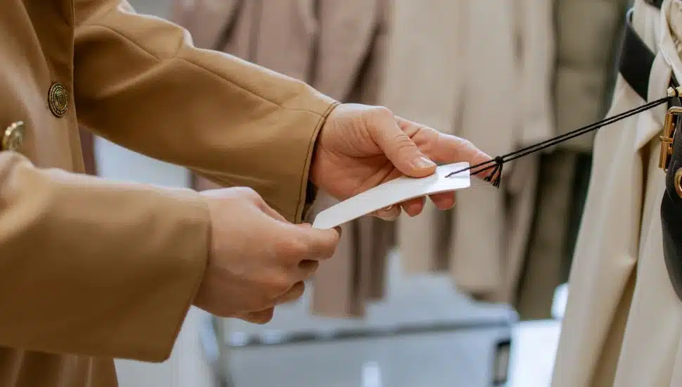 Woman's hands holding price tag mockup in clothing store.