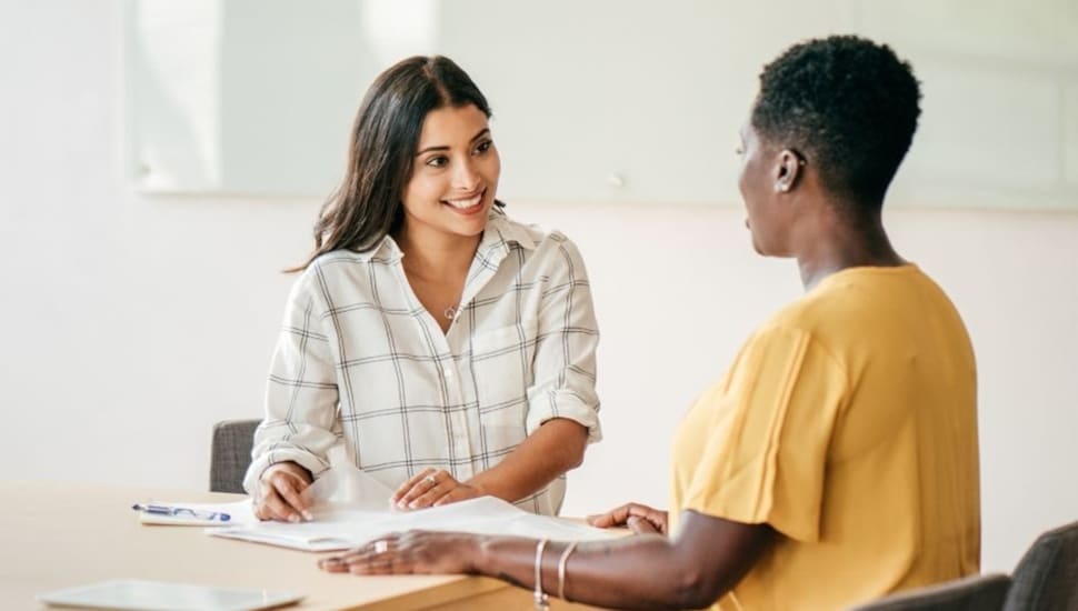 Woman interviews another woman at a desk.