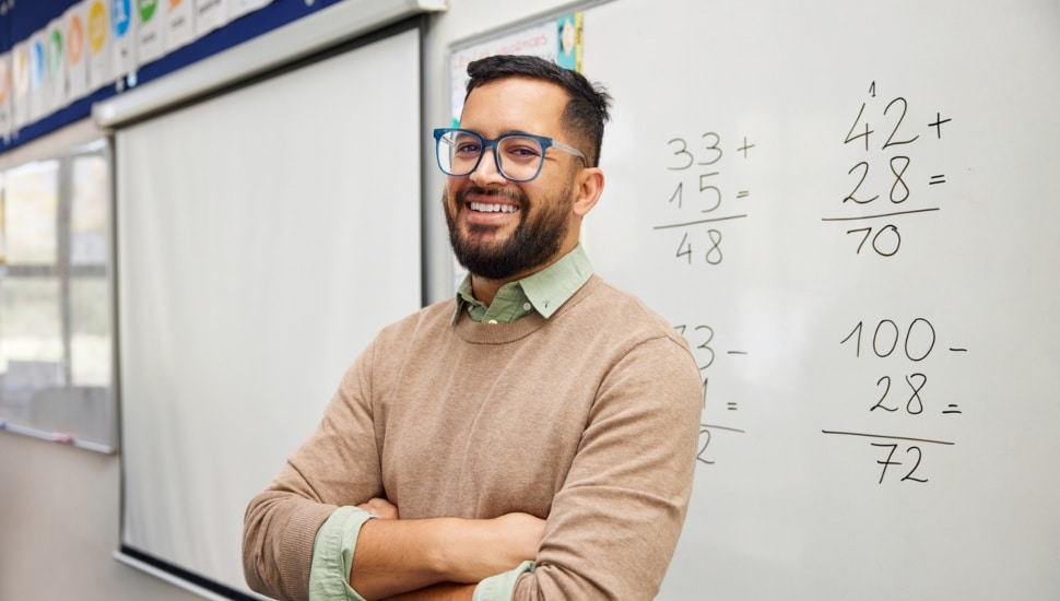 A teacher in front of a white board teaching a class.