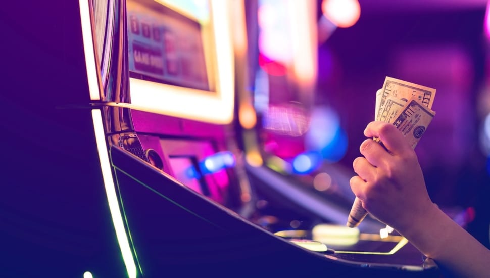 A female gambler holds money and is ready to win at slot machines.