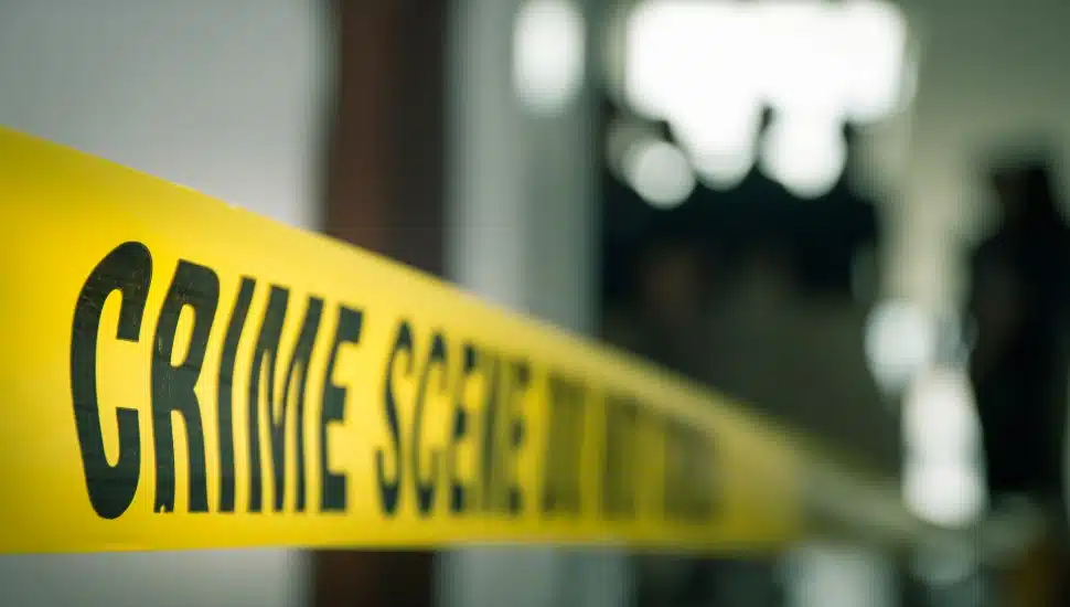 Crime concept by police line tape with blurred forensic law enforcement background in cinematic tone and copy space.