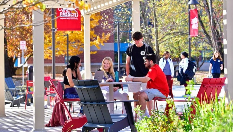 College students mingle outdoors in the fall.