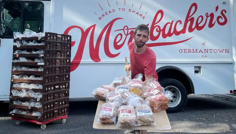 Merzbacher's founder Peter Merzbacher in front of a Merzbacher's truck holding a tray of bread.