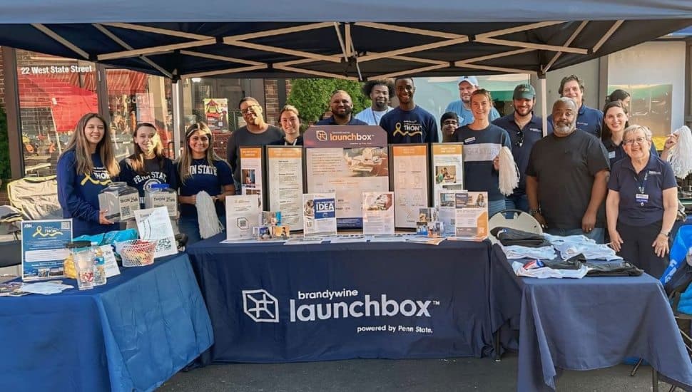 Members of the Penn State Alumni Society standing behind tables promoting the Brandywine Launchbox at Media Borough’s “Dining Under the Stars.”