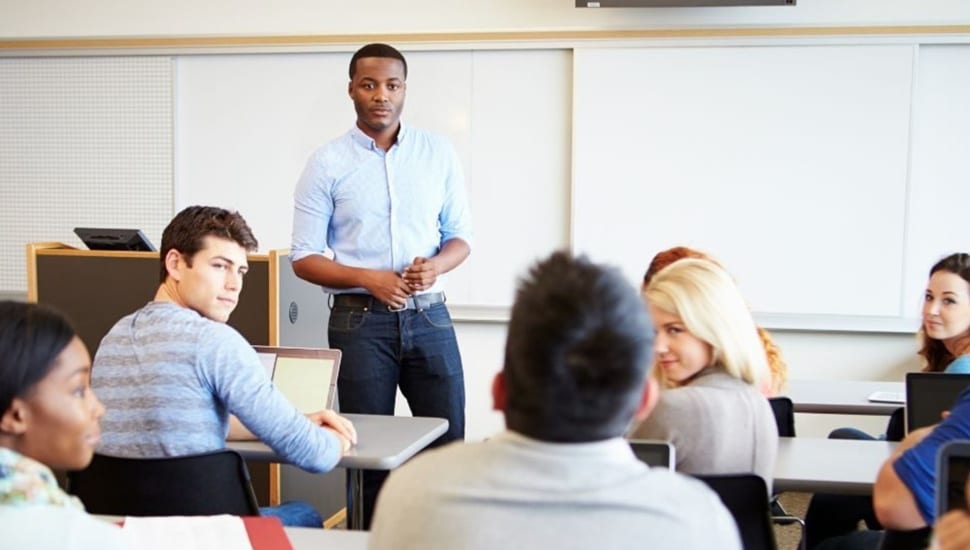Teacher stands in classroom full of students.