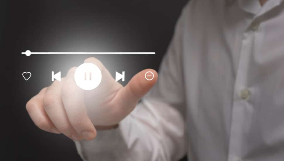 Businessman hand touching virtual icon of media player on virtual screen.
