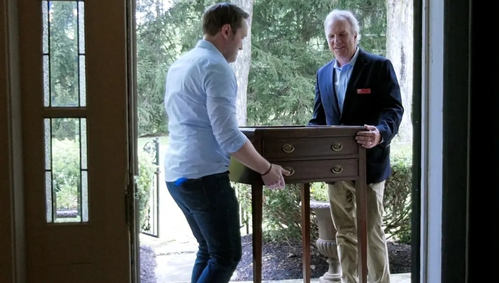 A desk being carried by two men.