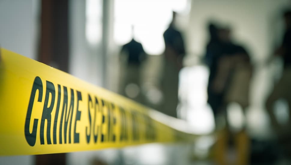 crime scene tape with blurred forensic law enforcement background in cinematic tone and copy space.