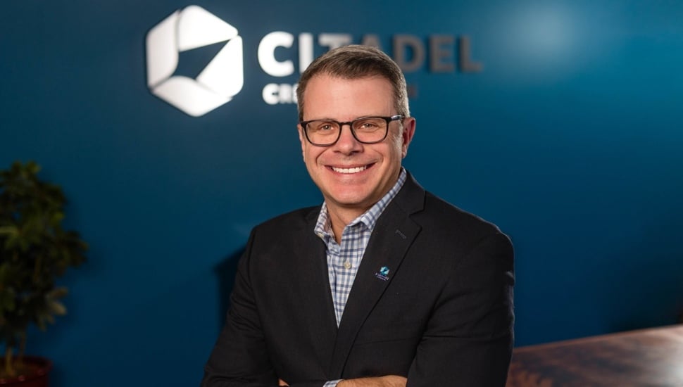 Middle-aged man in glasses poses for corporate headshot.
