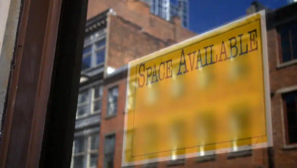 A 'For Lease' sign hangs in a storefront window.
