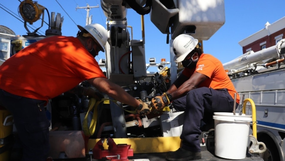 Two utility workers in orange shirts.
