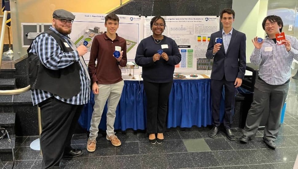 Penn State Brandywine engineering students with Cornerstone Engineering Design standing in front of a table at a public event.