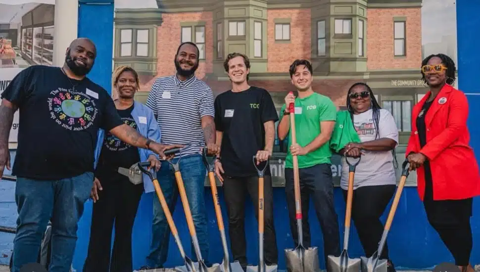 Seven people holding a shovel to signify a groundbreaking.