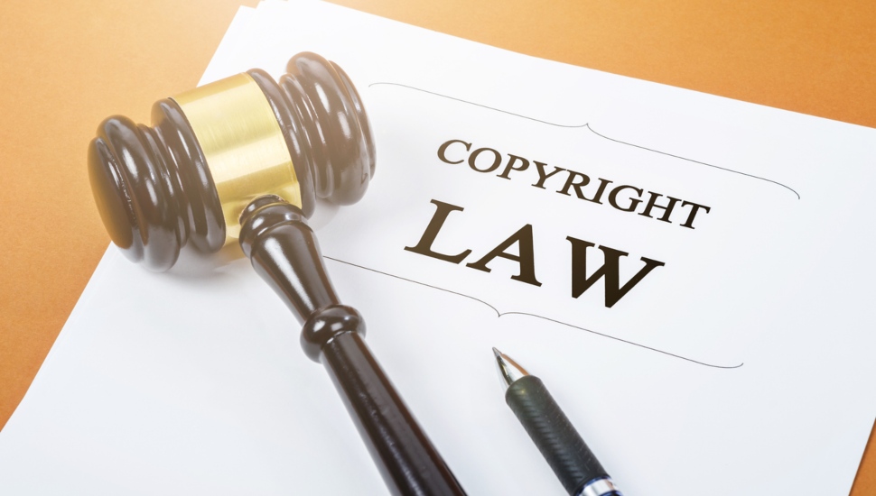 A paper with the title "Copyright Law" written on it, with a gavel and a pen resting on the paper.