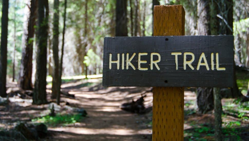 A sign that reads 'Hiker's Trail' in front of a path in the woods.