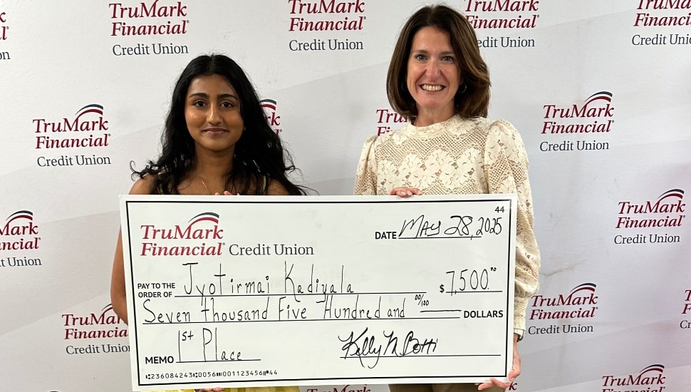 Credit union CEO presents giant check to high school student.
