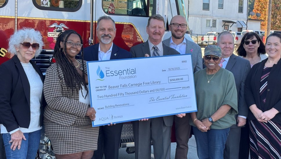 A group of community leaders and representatives from The Essential Foundation present a 0,000 donation check to the Beaver Falls Carnegie Free Library for building renovations, standing in front of a fire truck in Beaver Falls, Pennsylvania.
