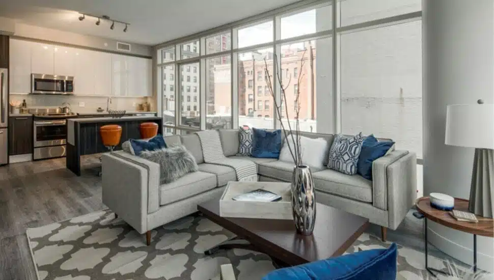An apartment living room with a couch, pillows, a building in the background.