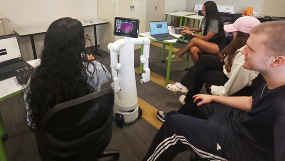 College students work with humanoid robot.