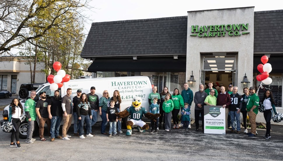 Eagles cheerleaders and bank representatives pose for picture with employees of carpet company.