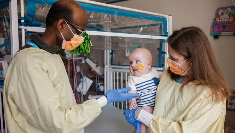 Cardiologist Kiran Musunuru and pediatric geneticist Rebecca Ahrens-Nicklas hold KJ Muldoon after he received an infusion of a drug custom-made for him.