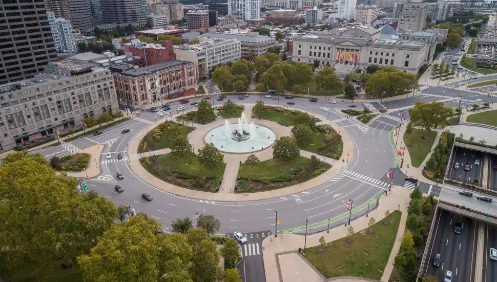 Traffic circle center features a large fountain with whimsical statuary, garden areas with benches.