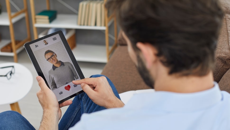 Man on digital tablet looks at a profile of a young woman.