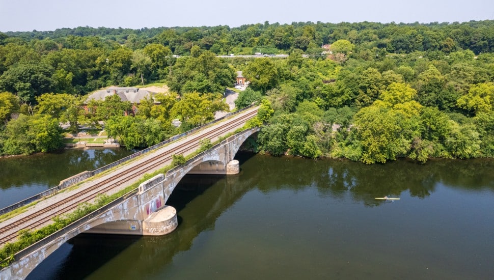 A bridge over The schuykill river with a train on the tracks.