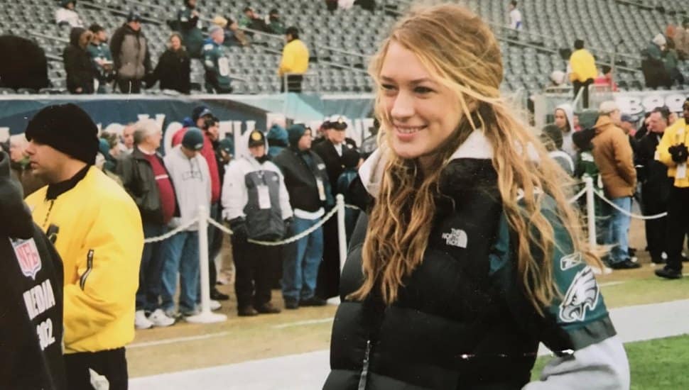 A younger Devan Kaney at age 15 on the sidelines of Lincoln Financial Field waving to Philadelphia Eagles fans.
