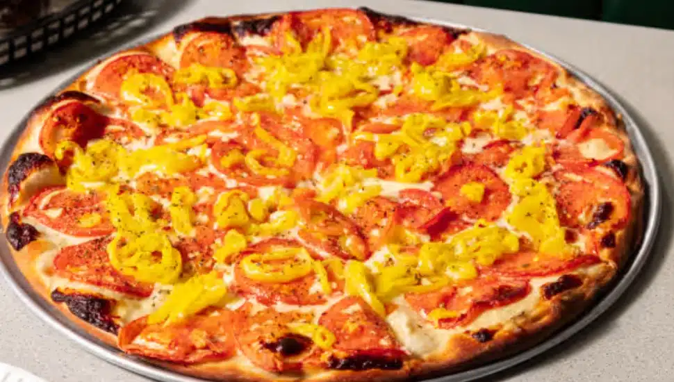 A pizazz pizza with American cheese, tomatoes, banana peppers, and oregano, with no sauce.