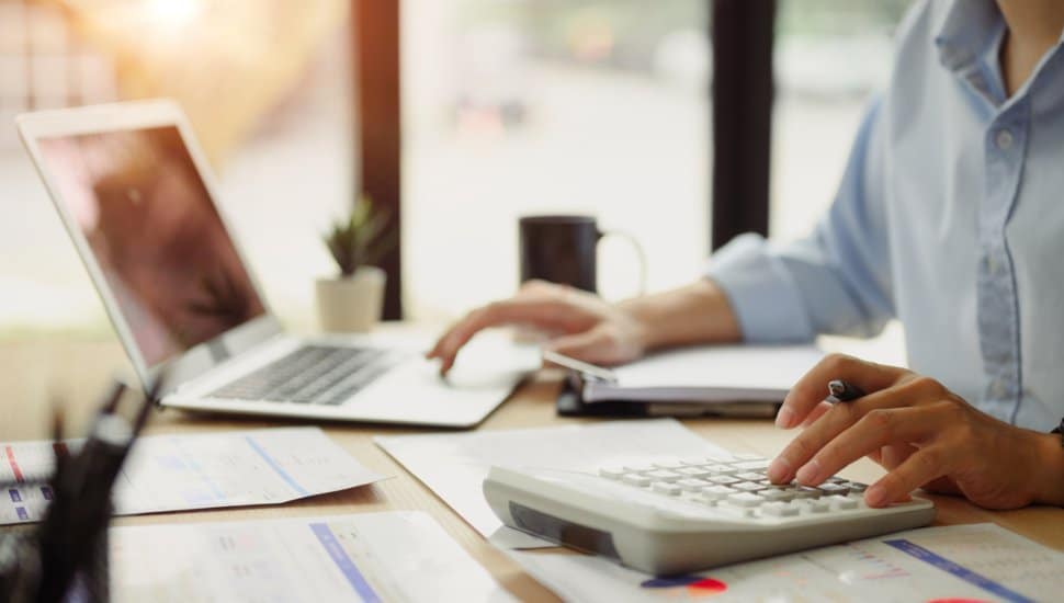 Businessman calculating finances at office desk.