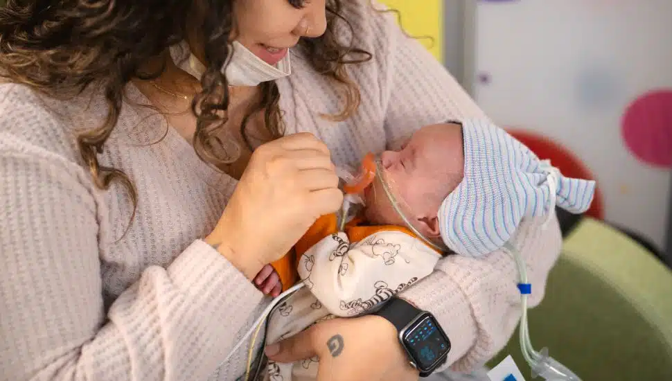 Mother holds her baby with the new cap at Penn Medicine.
