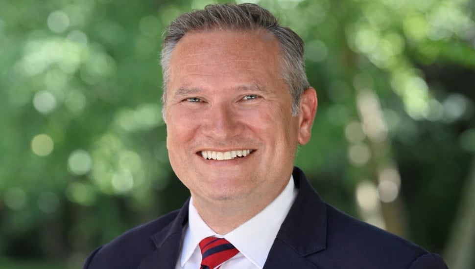 Headshot of middle-aged man in blue suit and red tie.