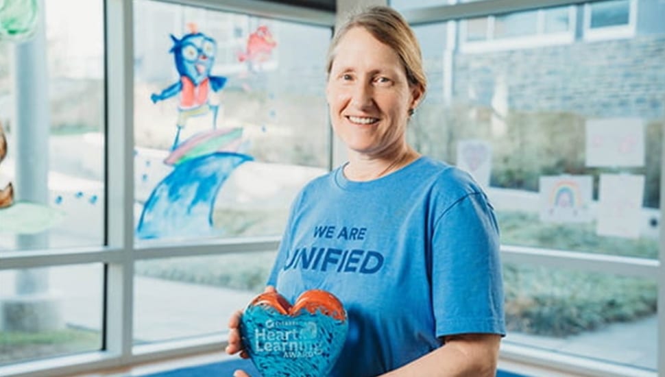 Female teacher holds glass heart award.