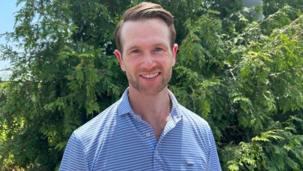 Tyler McNeil headshot outside with trees in background.