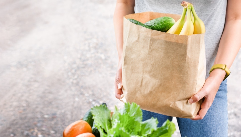 A woman holding a paper bag with groceries.