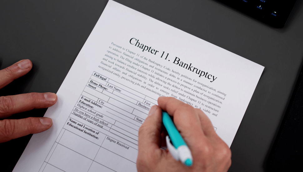 Person writing on a Chapter 11 Bankruptcy page.