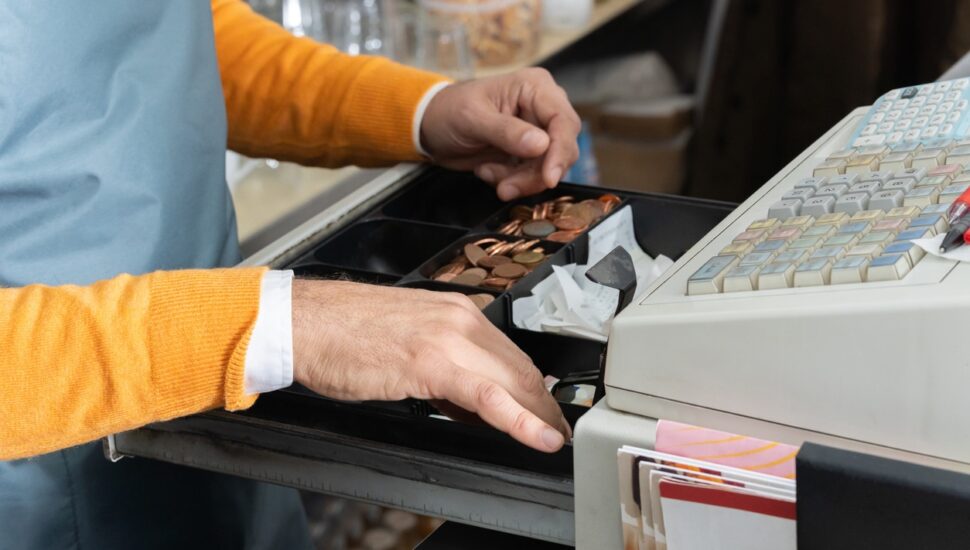 Cashier´s hands searching for change in an open cash register.