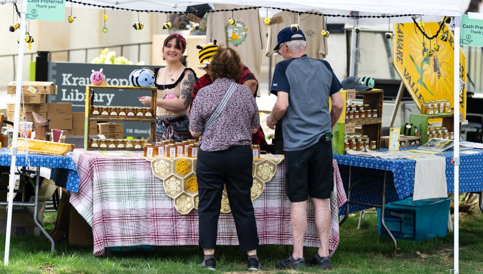 Older couple visits vendor’s table at fair.