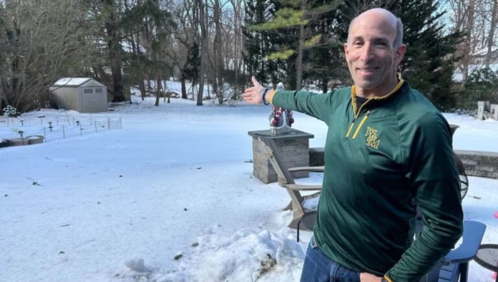 Bob Mina points to snowy backyard.
