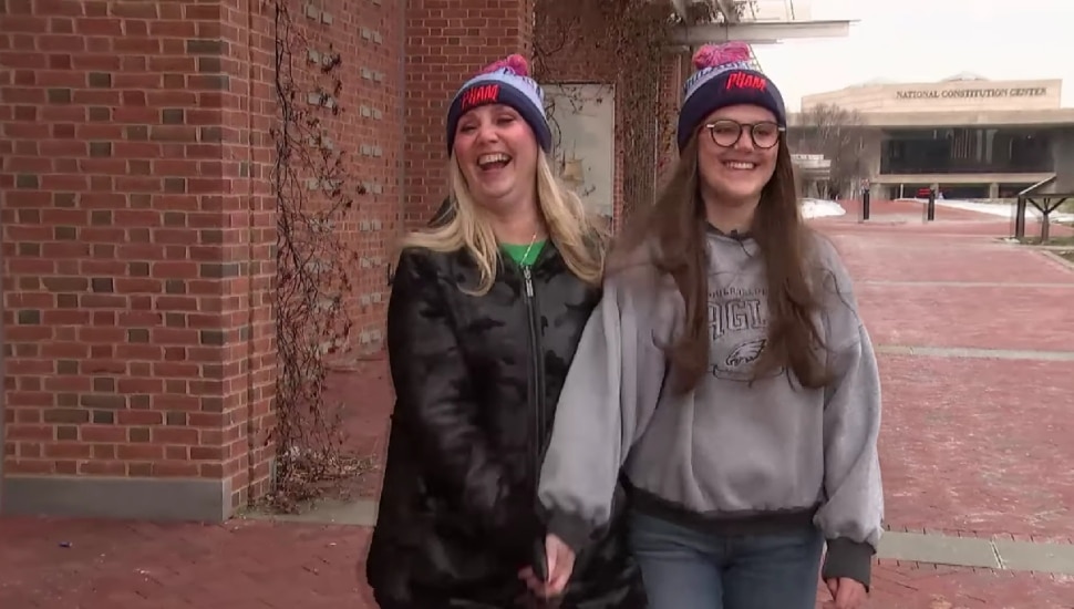 Kathy (left) and Kaitlin (right) Nasevich hold hands while walking.