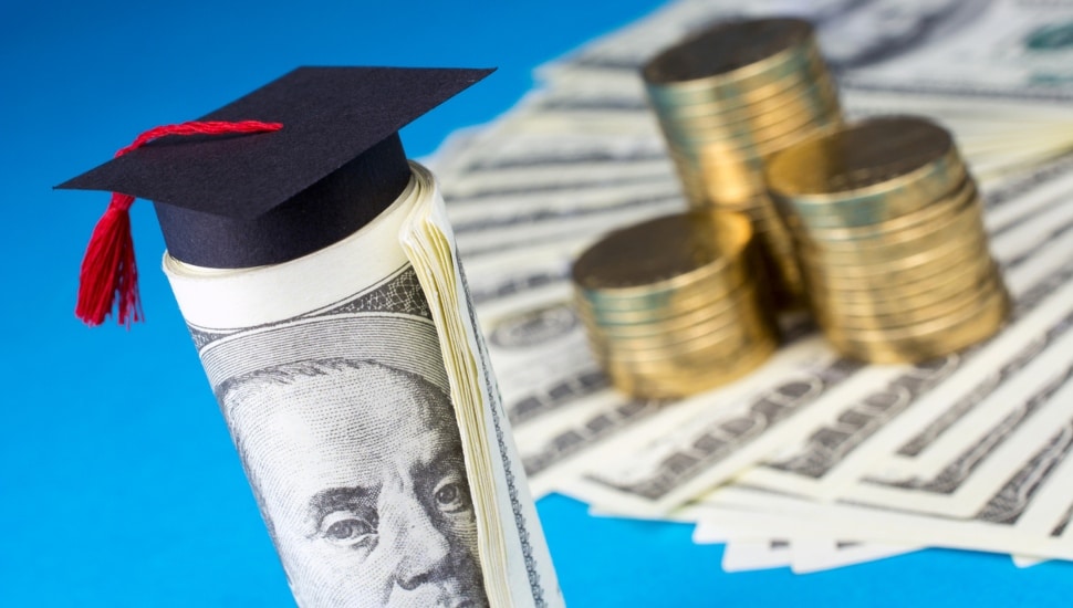 Graduation mortarboard, money, and gold coins on blue background.