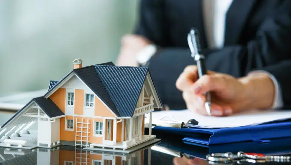 A hand signing a purchase agreement for a new home.