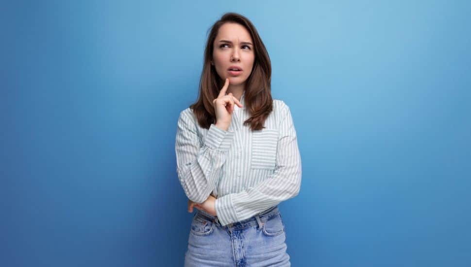 Thoughtful 25 year old brown-haired female person dressed in a striped blouse.