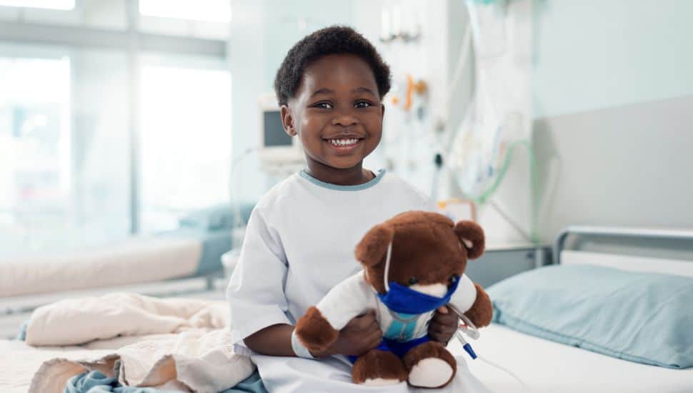 Healthcare, black child and teddy bear in hospital for surgery recovery, patient and healthy results. Face, boy kid and bed for medical, wellness or toy for relax on bed, rehabilitation and happiness.