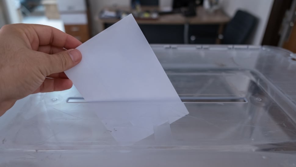 A hand casting a ballot during an election.
