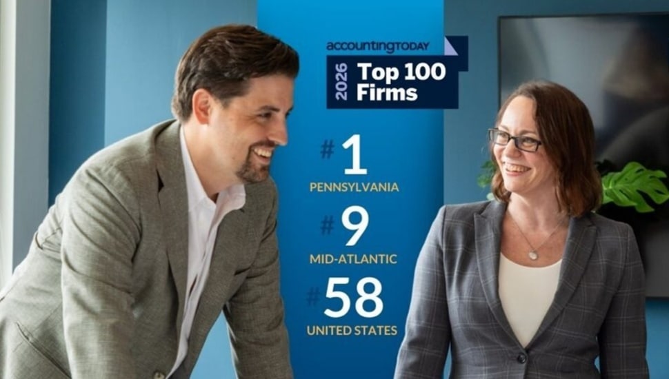 Male and female accountants smile at firm's recognition.