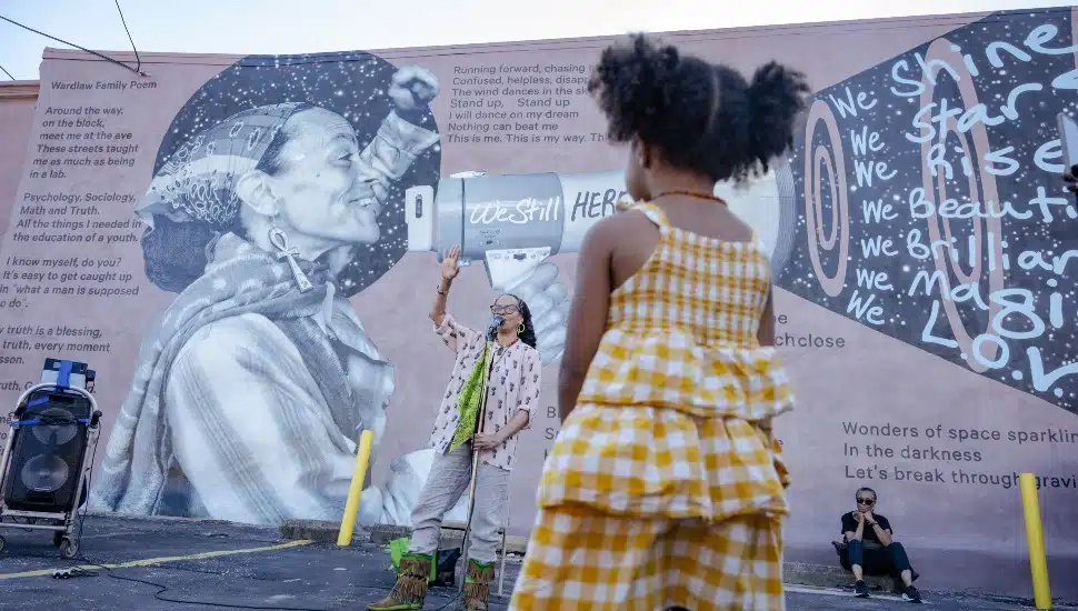 A child looking at an artist with art in the background.